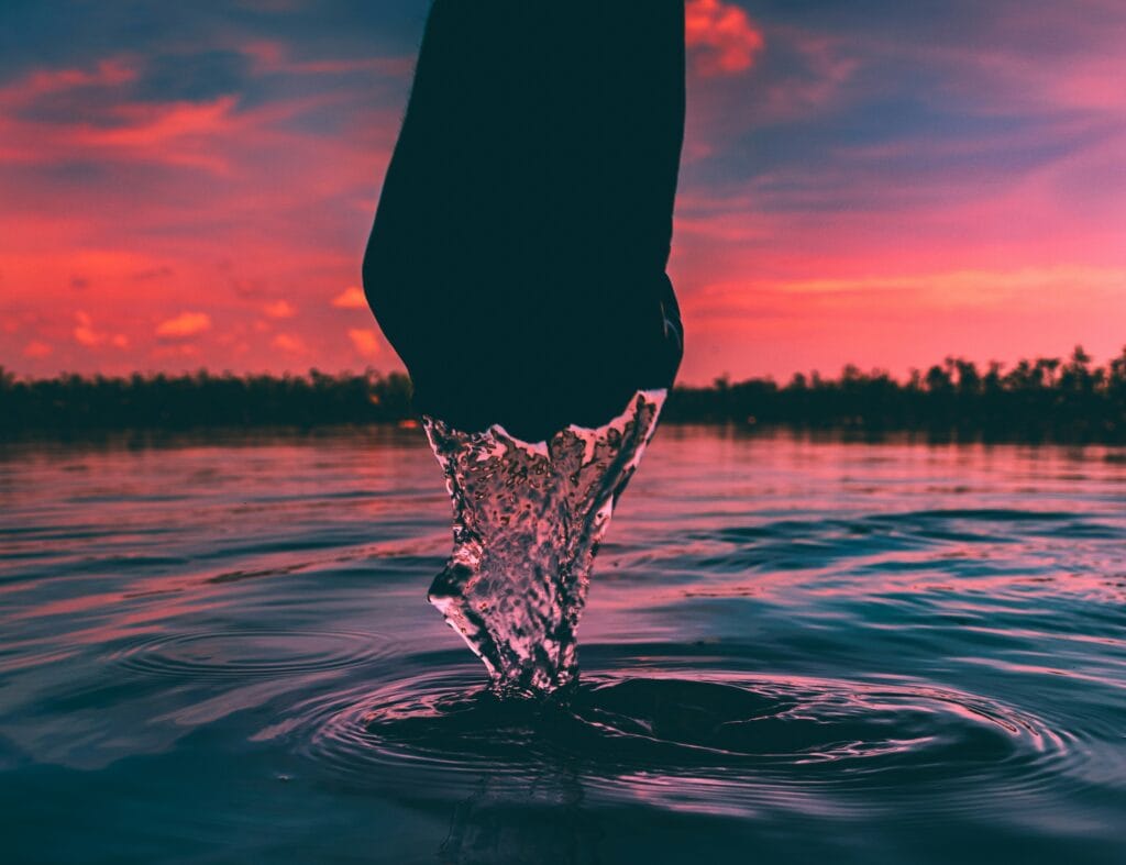 A person's hand holding water at sunset